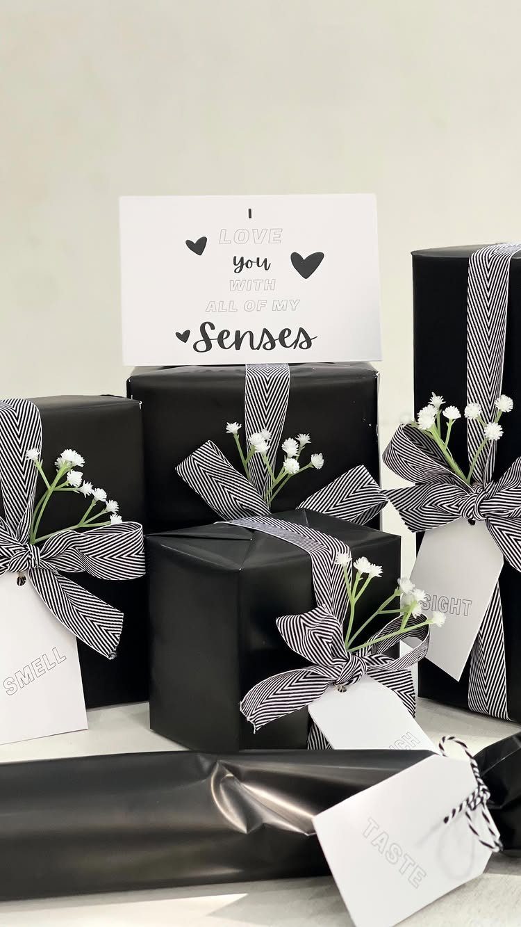 Black wrapped gifts with striped ribbons and tags for a five senses gift set