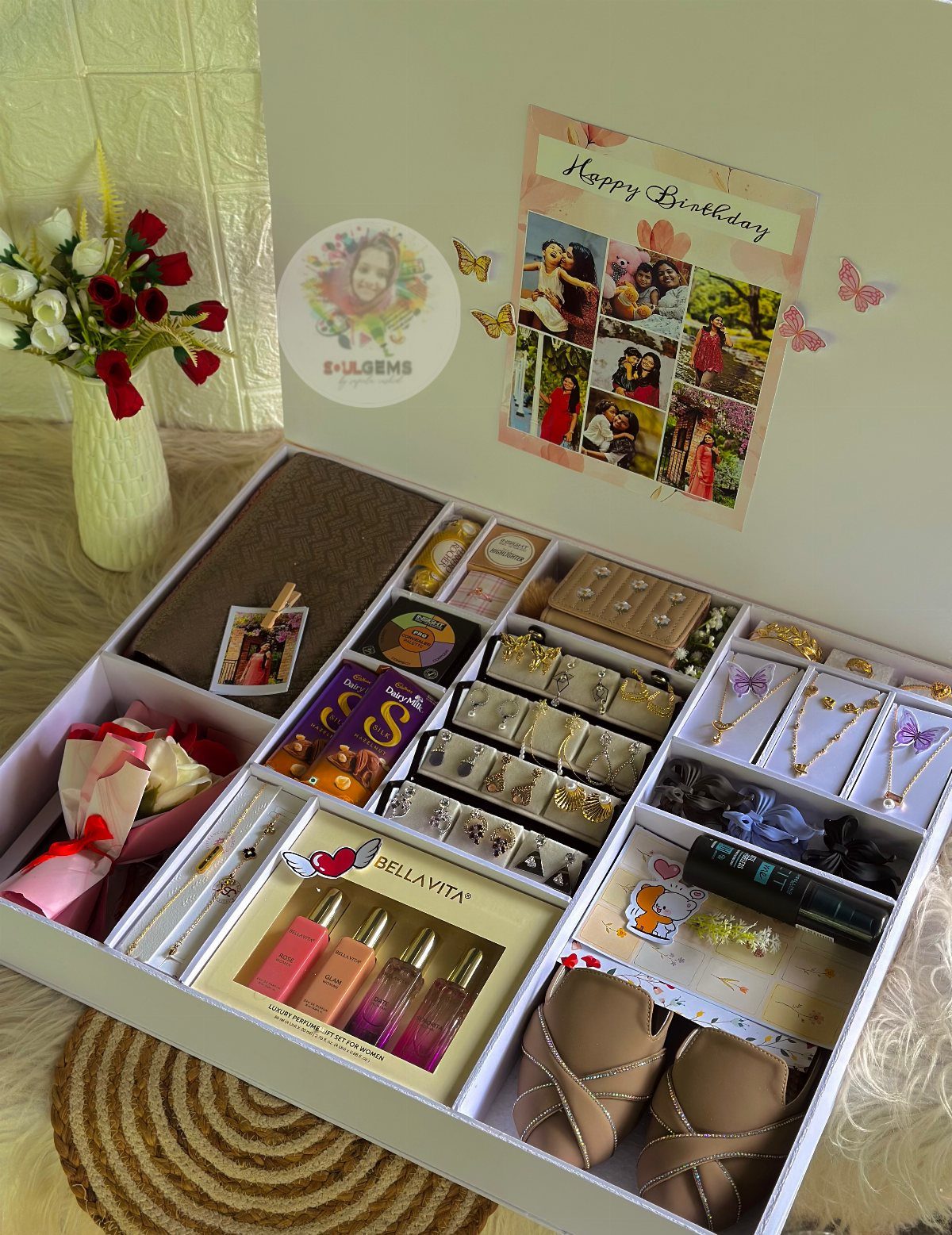 Gift box filled with perfumes, jewelry, and photos next to red roses