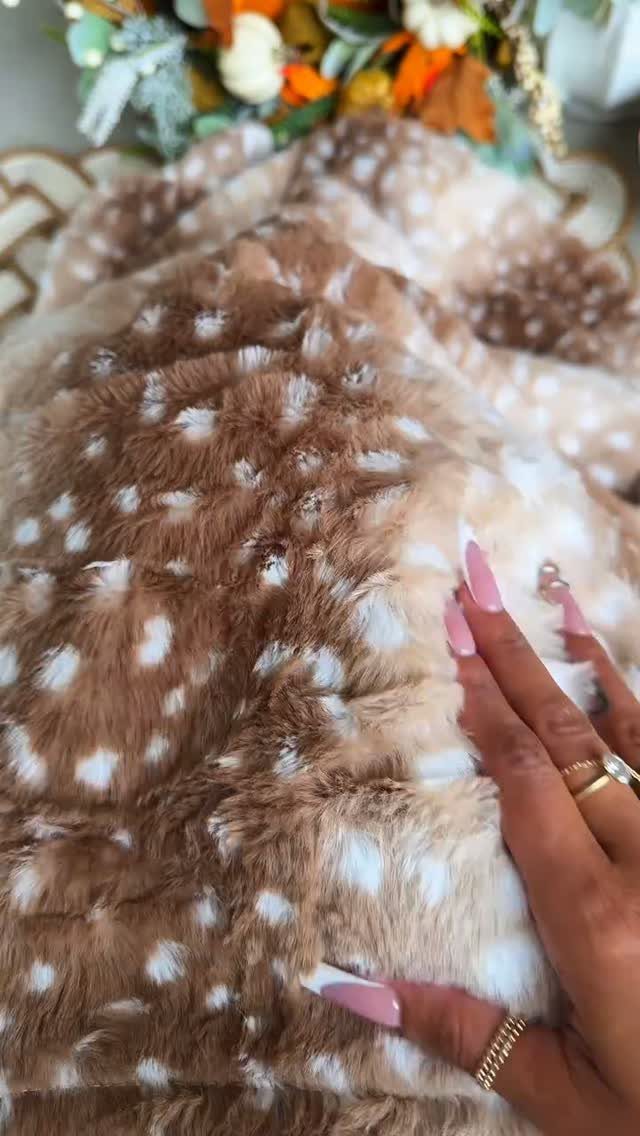 Brown and white spotted faux-fur blanket being touched by a hand with rings.