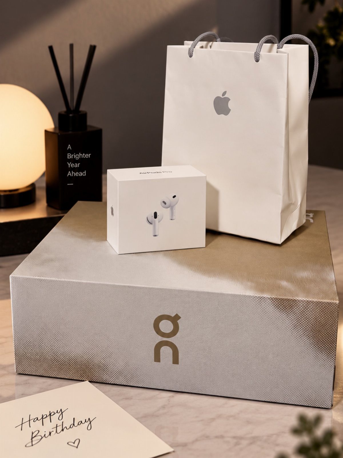 AirPods box and Apple bag on a grey shoe box with birthday card.