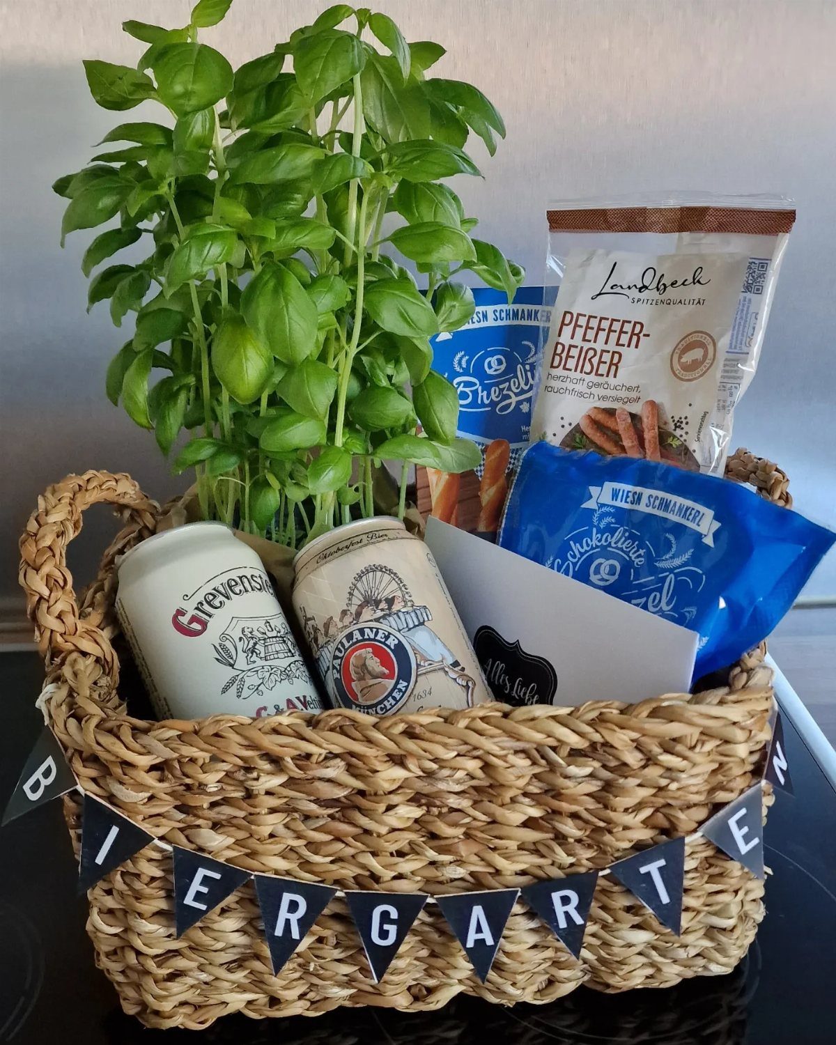 Wicker gift basket with basil plant, beer cans, and pretzels for a beer garden theme