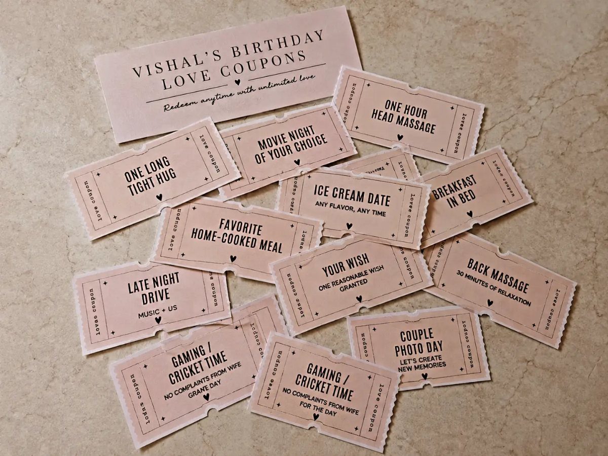 Handmade pink birthday love coupons scattered on a light stone surface for a boyfriend.