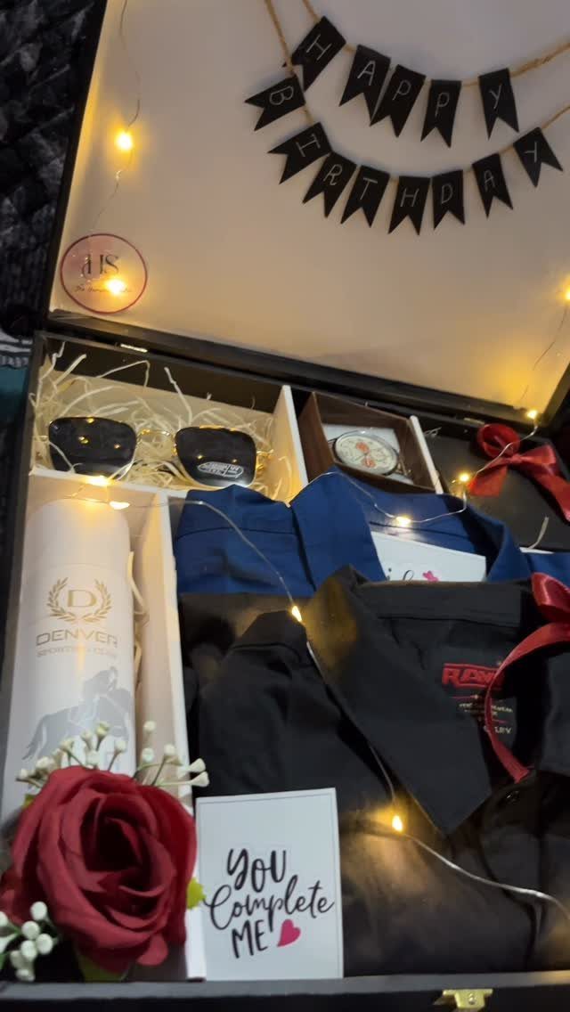 Birthday gift box with shirts, sunglasses, watch, bottle, and a red rose.