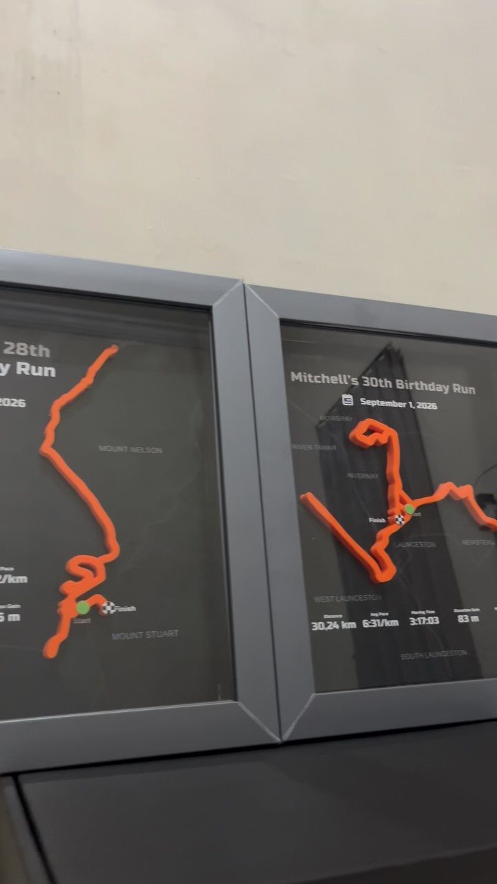Framed GPS route maps of birthday runs displayed on a dark surface.