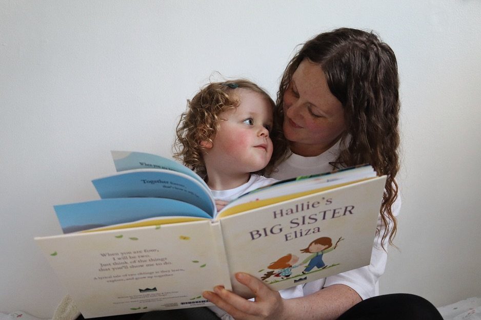 Woman and young girl reading a personalized Big Sister storybook together.