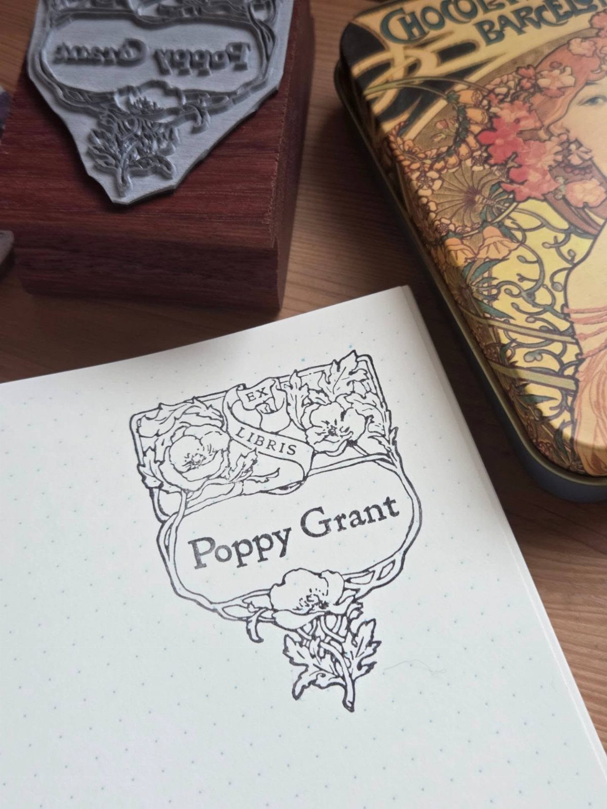 Personalized bookplate stamp on a white notebook with floral designs and name Poppy Grant.