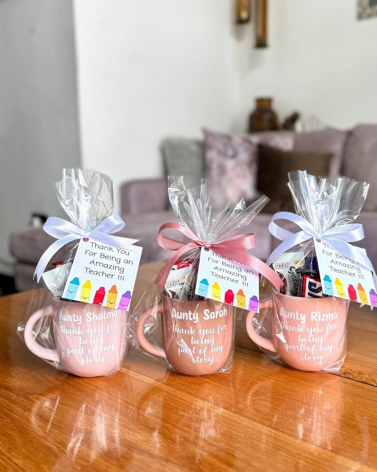 Three pink gift mugs wrapped in cellophane with ribbons and teacher thank you tags.