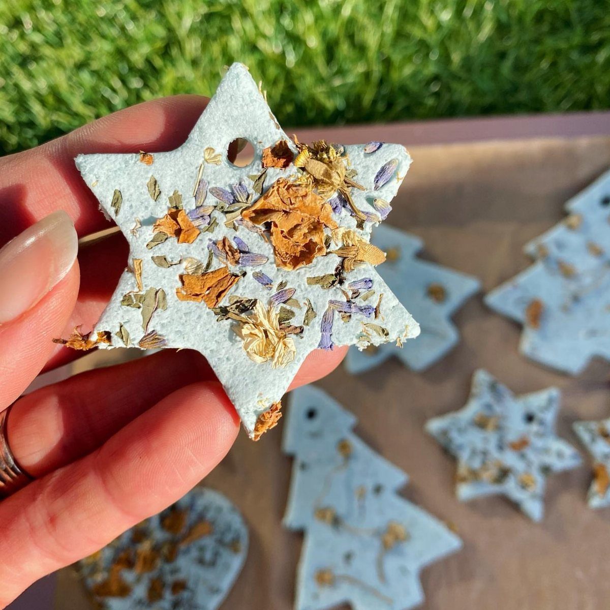 Star-shaped salt dough ornament with dried flower petals held by a hand.
