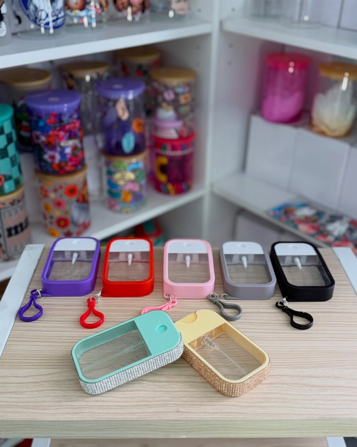 Colorful silicone hand sanitizer holders with clips arranged on a light wooden table.