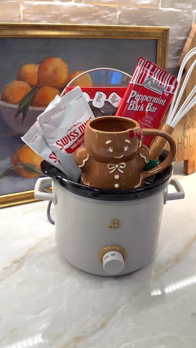 Gingerbread man mug and cocoa packets inside a white slow cooker gift basket.