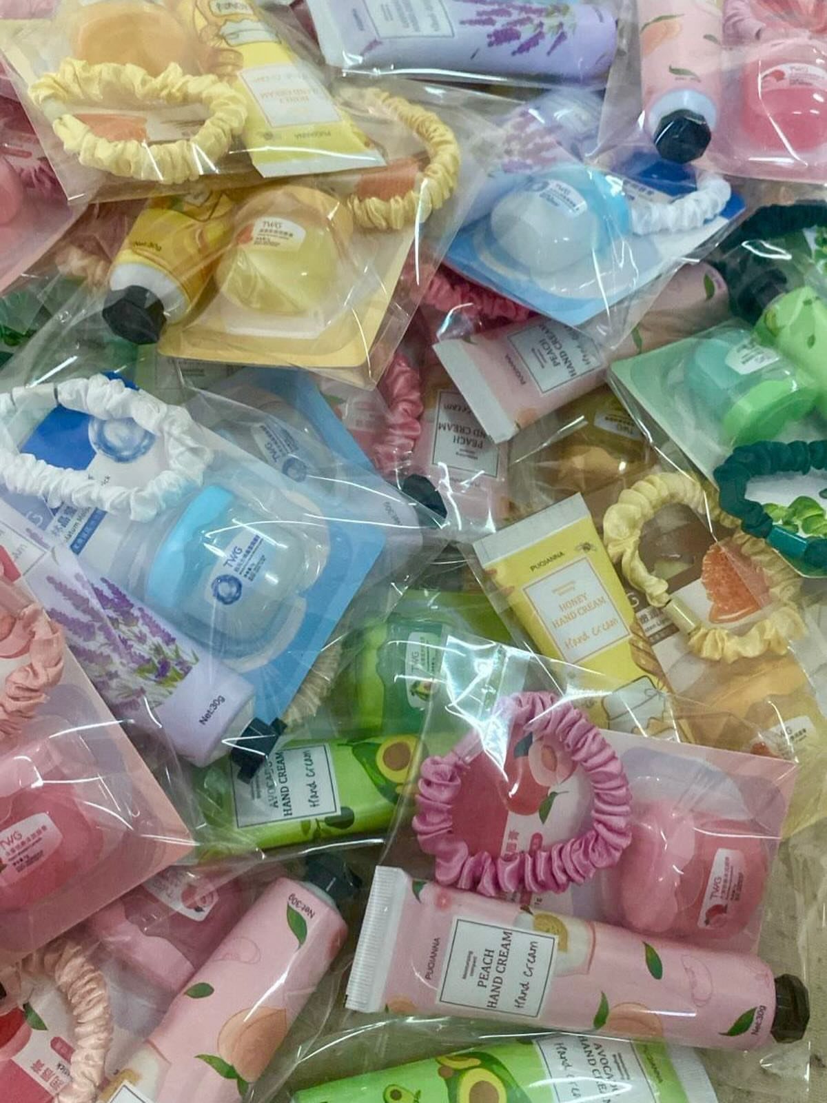 Small clear gift bags filled with colorful hand creams and hair scrunchies.