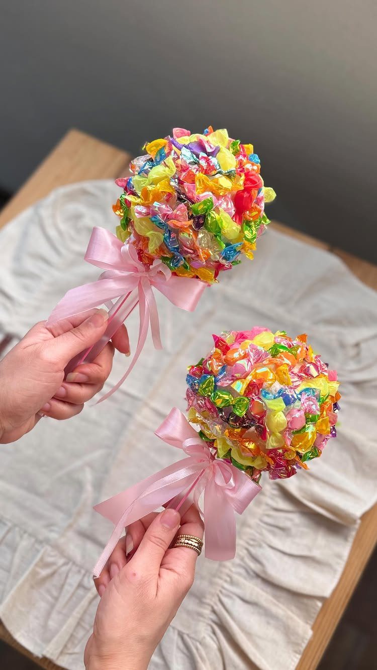 Two candy bouquets made of colorful wrapped sweets tied with pink ribbons.