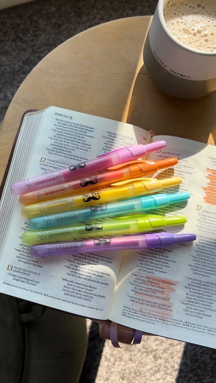 Colorful highlighter pens resting on an open Bible next to a cup of coffee