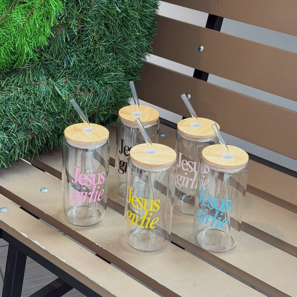 Four clear glass tumblers with bamboo lids and 'Jesus girlie' text in various colors.