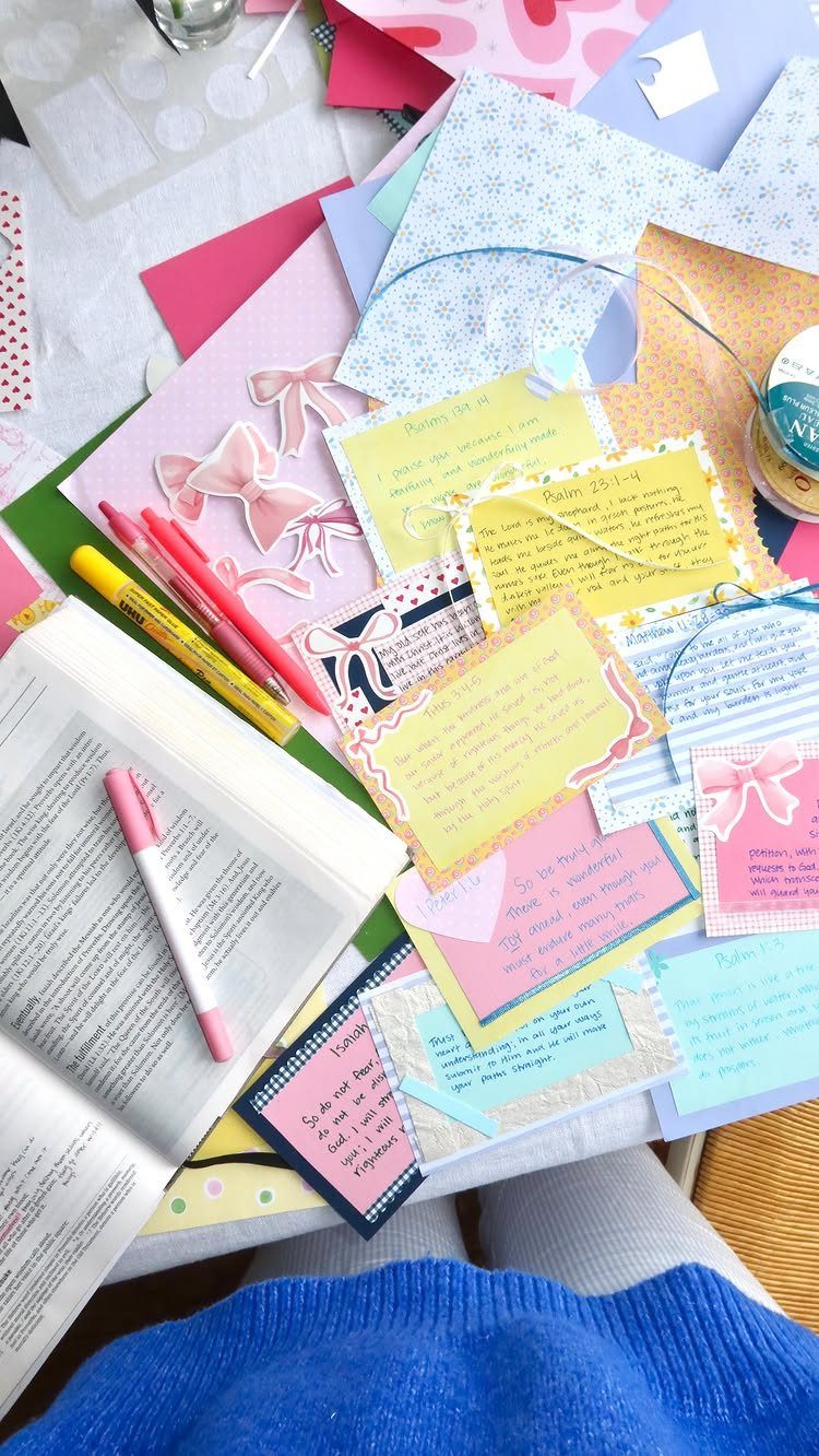Open Bible surrounded by colorful handwritten scripture memory cards and markers on a table