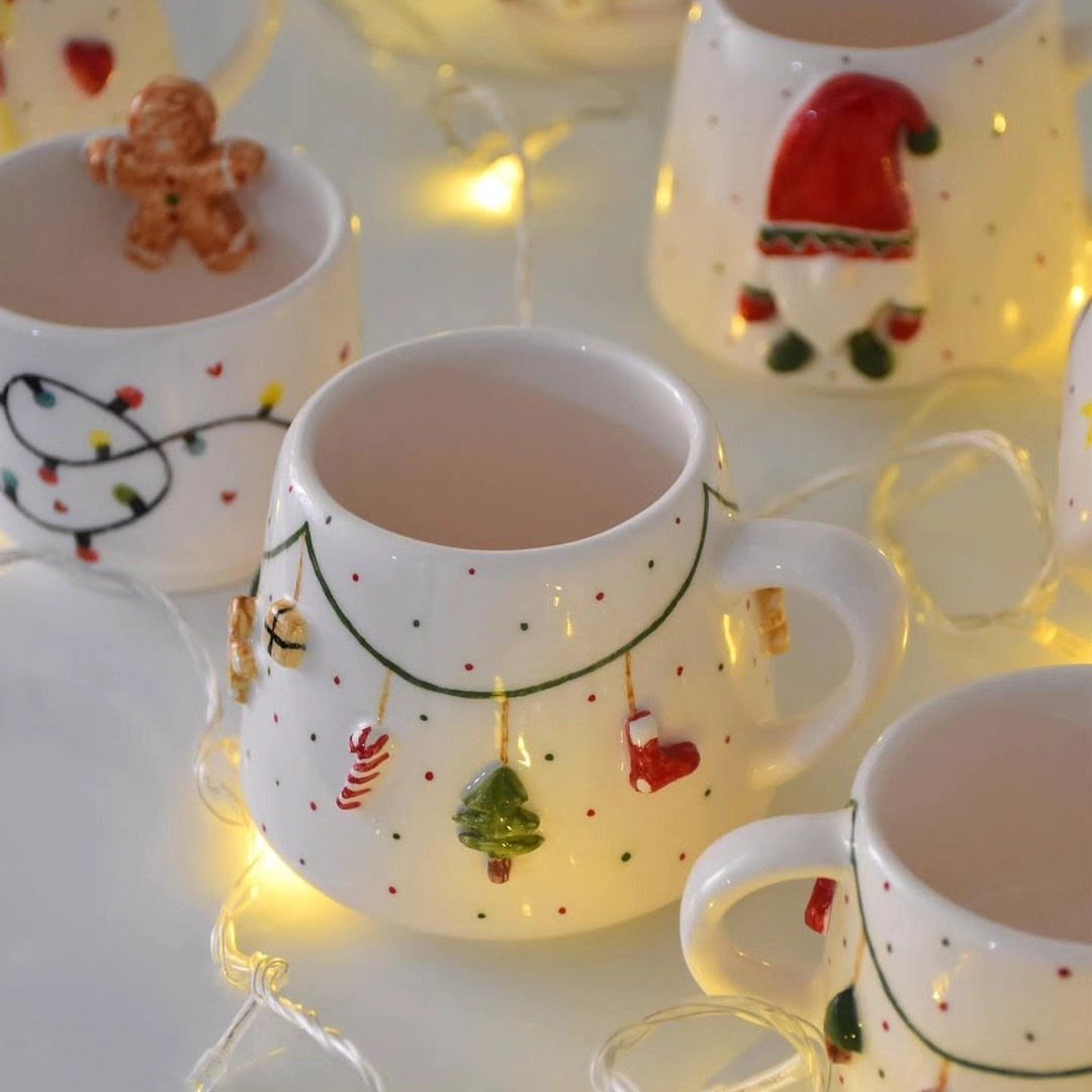White ceramic Christmas mugs with 3D embossed holiday decorations and warm fairy lights.