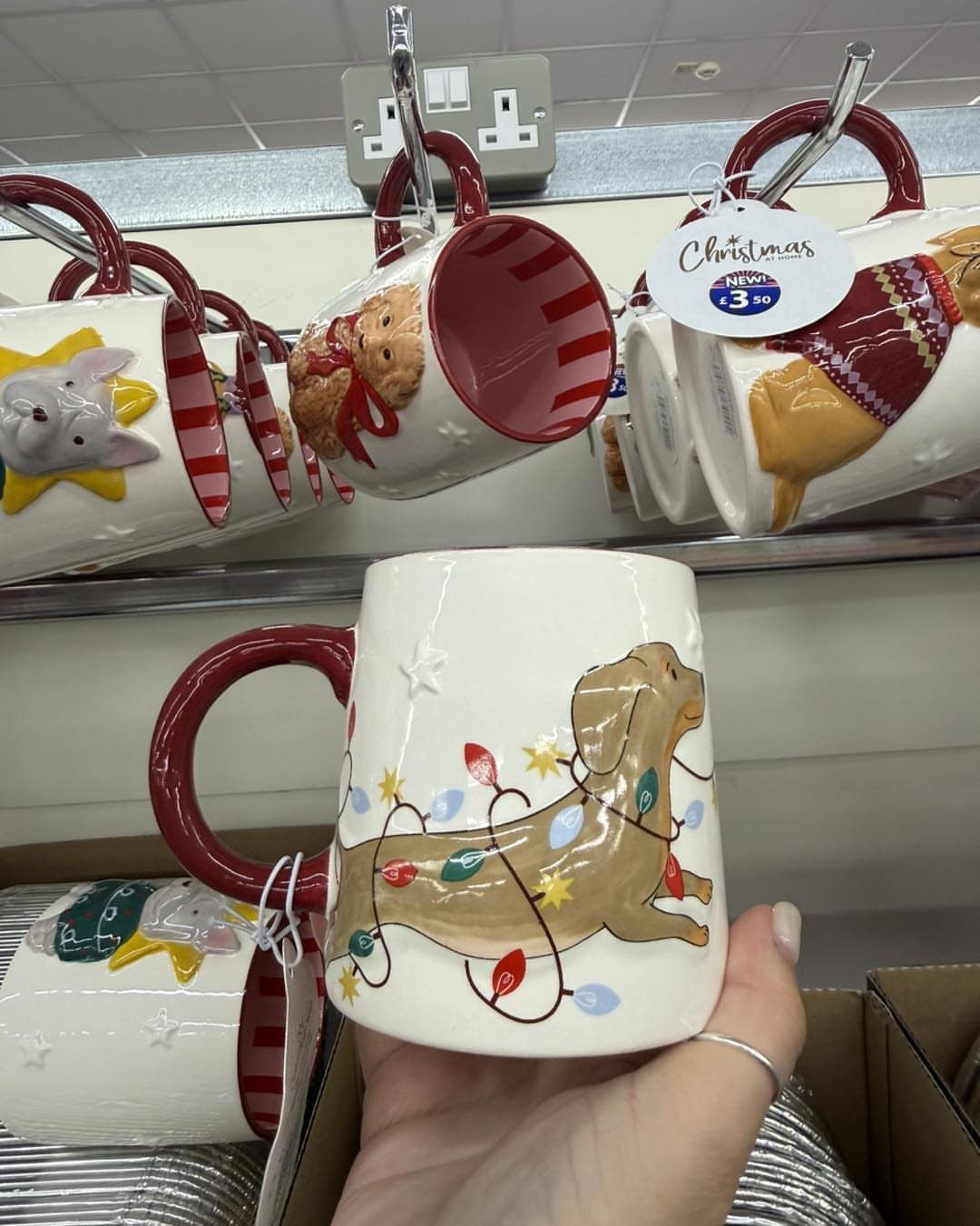 White ceramic mug with a red handle featuring a dachshund wrapped in Christmas lights