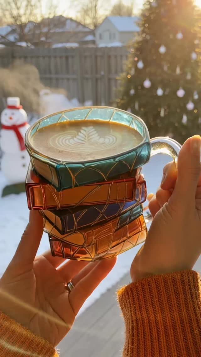 Stacked glass mugs with gold geometric patterns held against a snowy winter background.