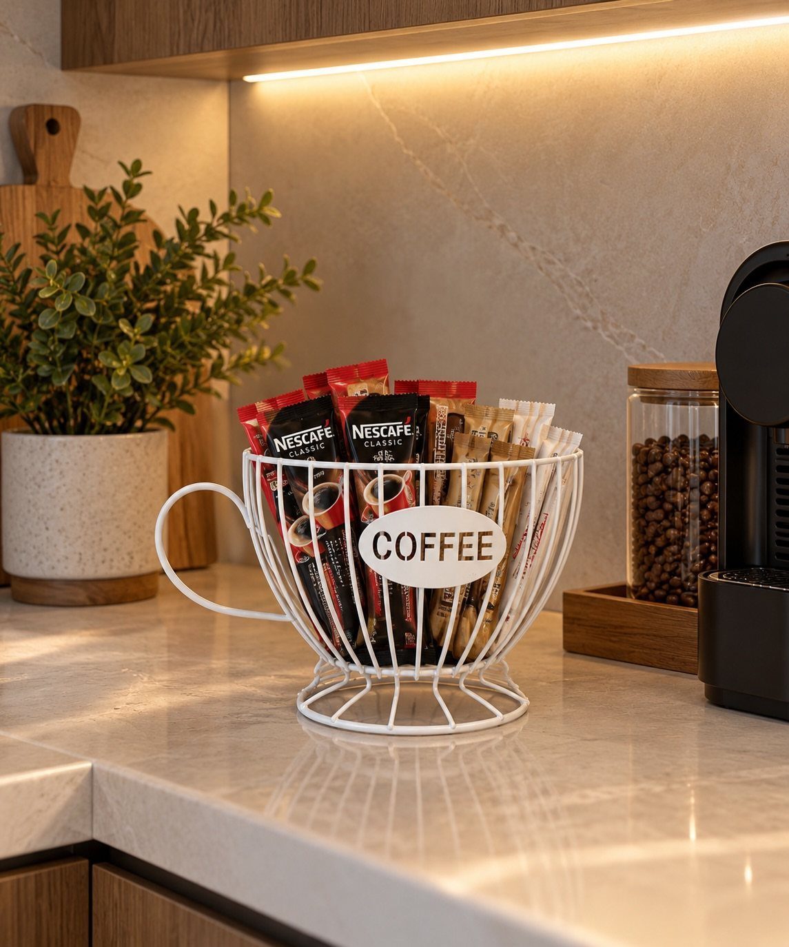 White cup-shaped wire basket filled with coffee sachets on a marble kitchen counter.