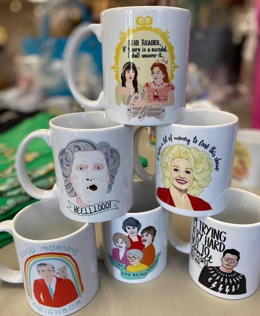 Six white ceramic coffee mugs with colorful character illustrations stacked in a pyramid.