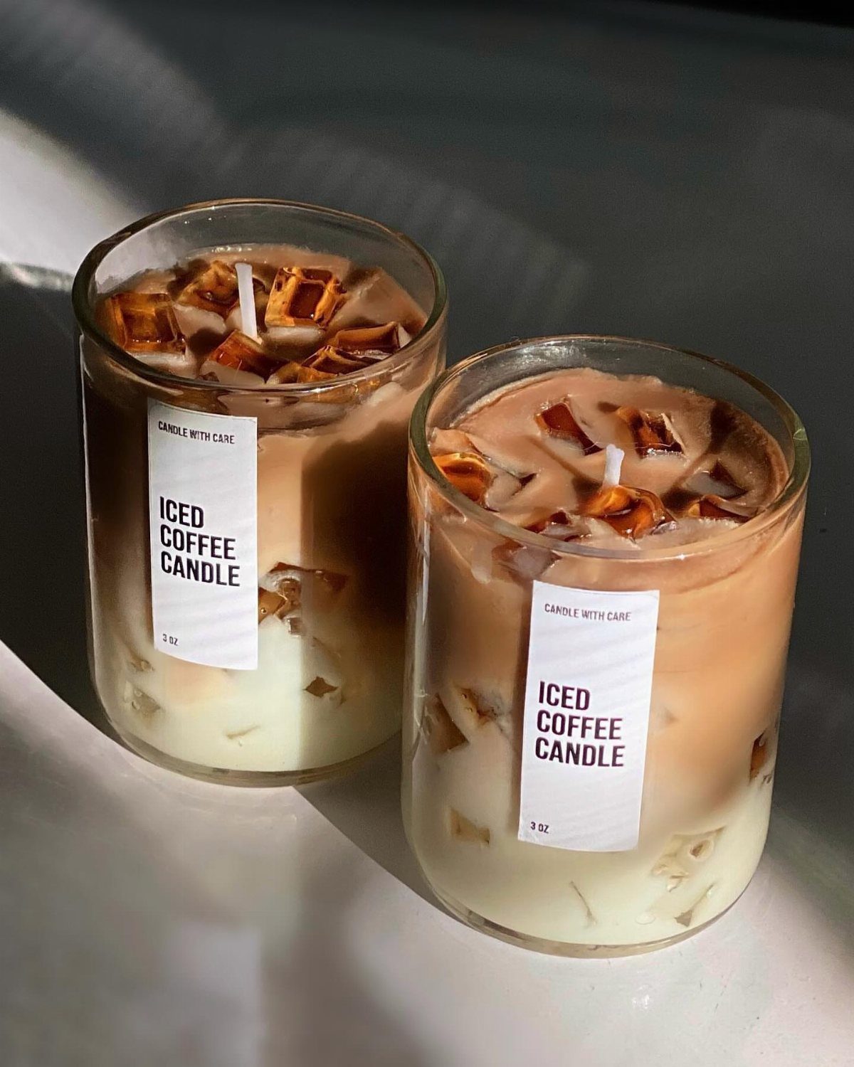 Two iced coffee candles in glass jars with brown and cream wax layers.