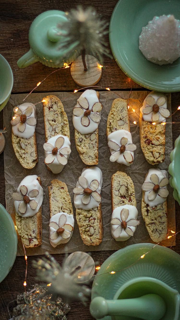Almond biscotti with white icing decorations on parchment paper with green teapots.