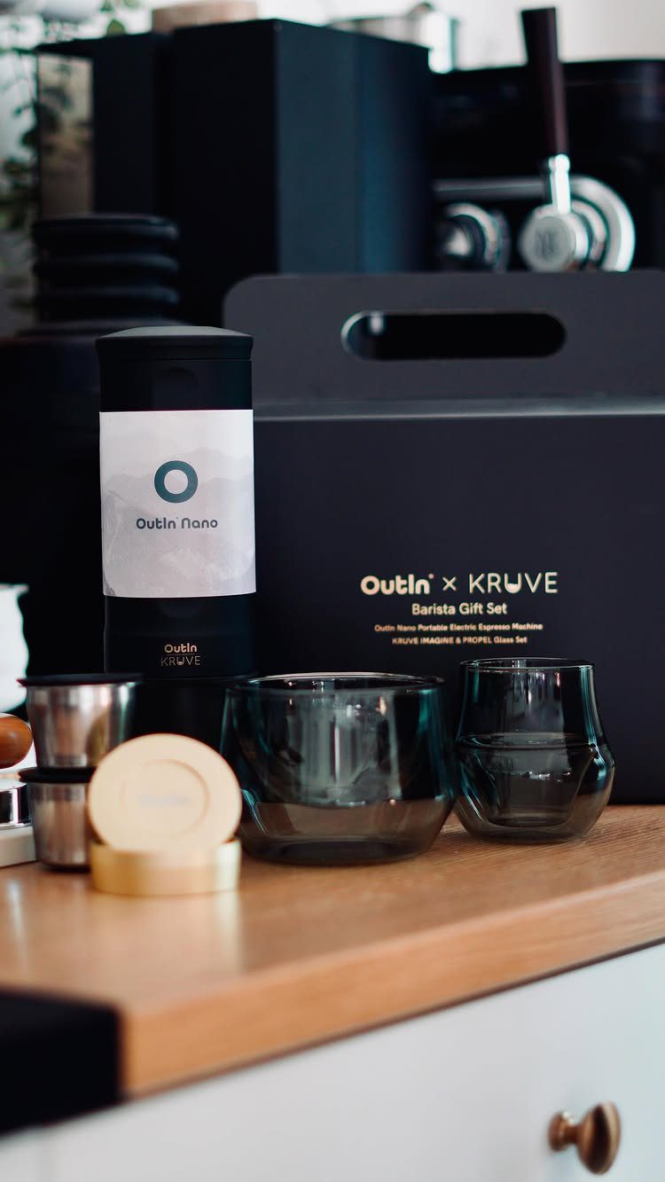 Barista gift set with black thermal bottle and tinted glasses on wooden counter