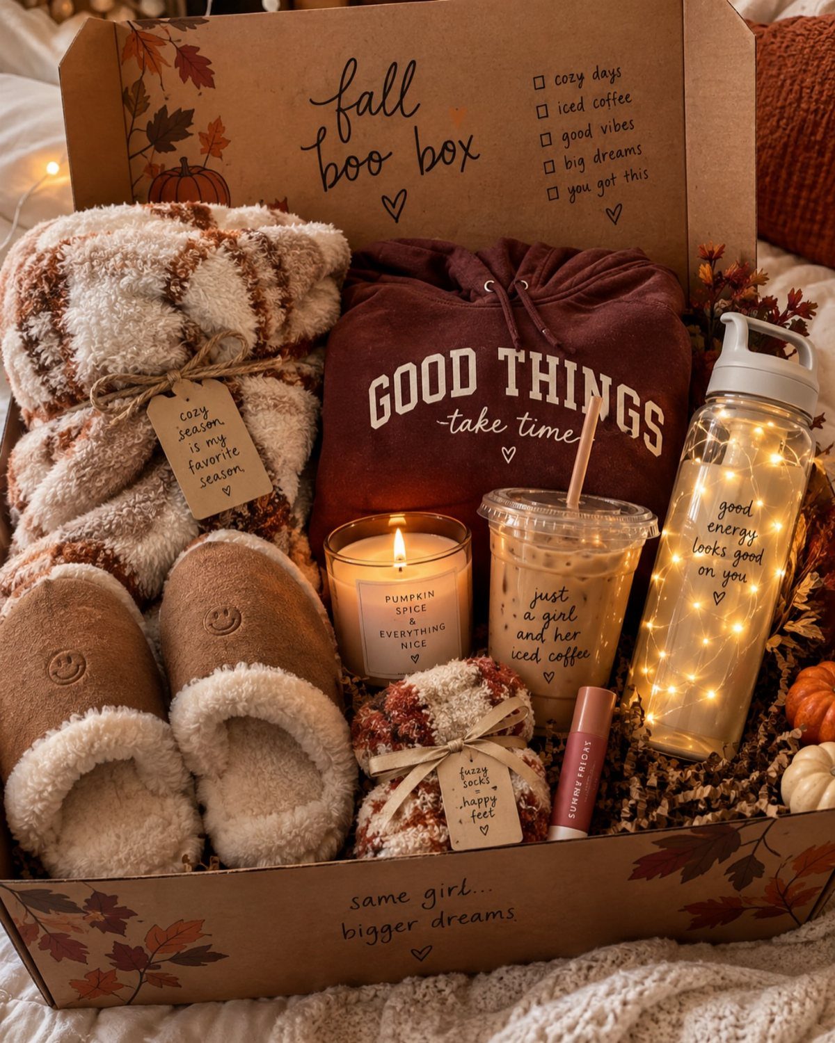 Fall gift box with a plaid blanket, pumpkin spice candle, and cozy accessories.