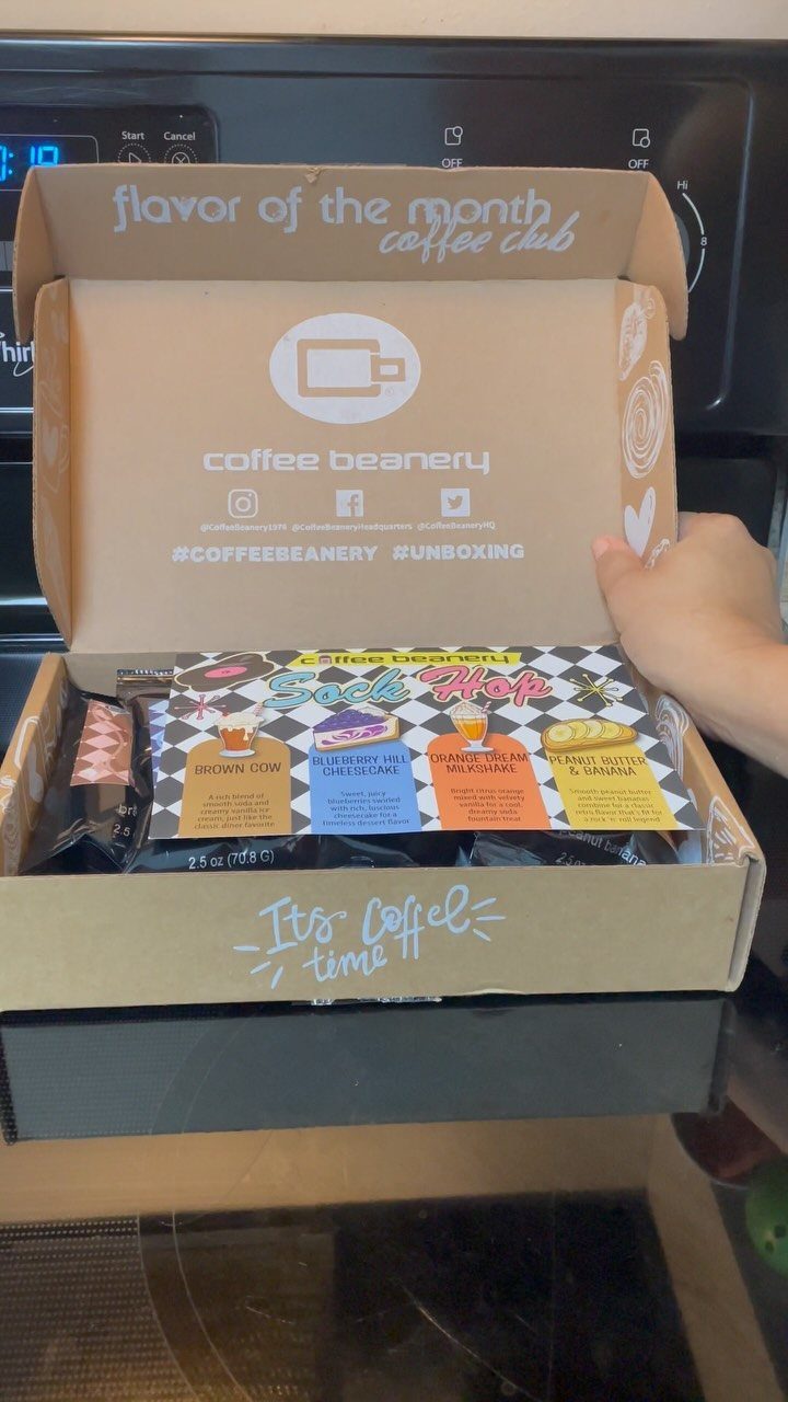 Open Coffee Beanery subscription box containing coffee bags and a colorful informational insert.