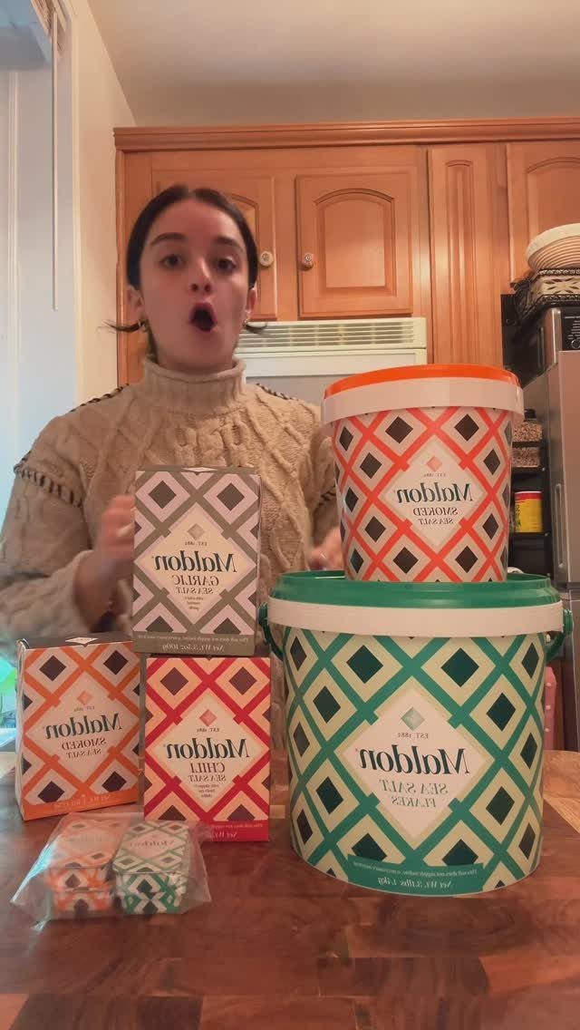 Woman surprised by a large bucket and boxes of Maldon sea salt.
