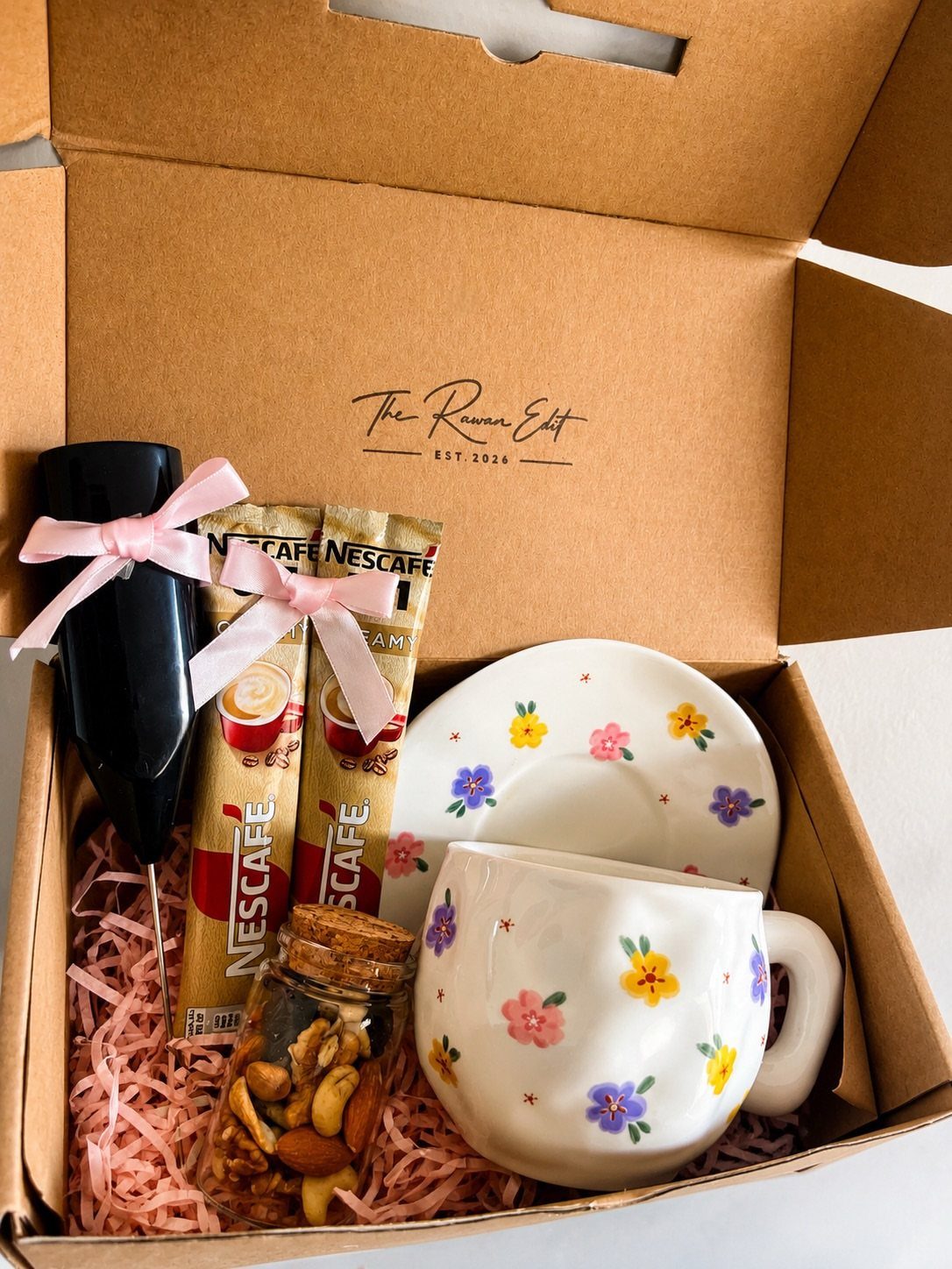 Coffee gift set with floral mug, Nescafe sachets, and nuts in a box.