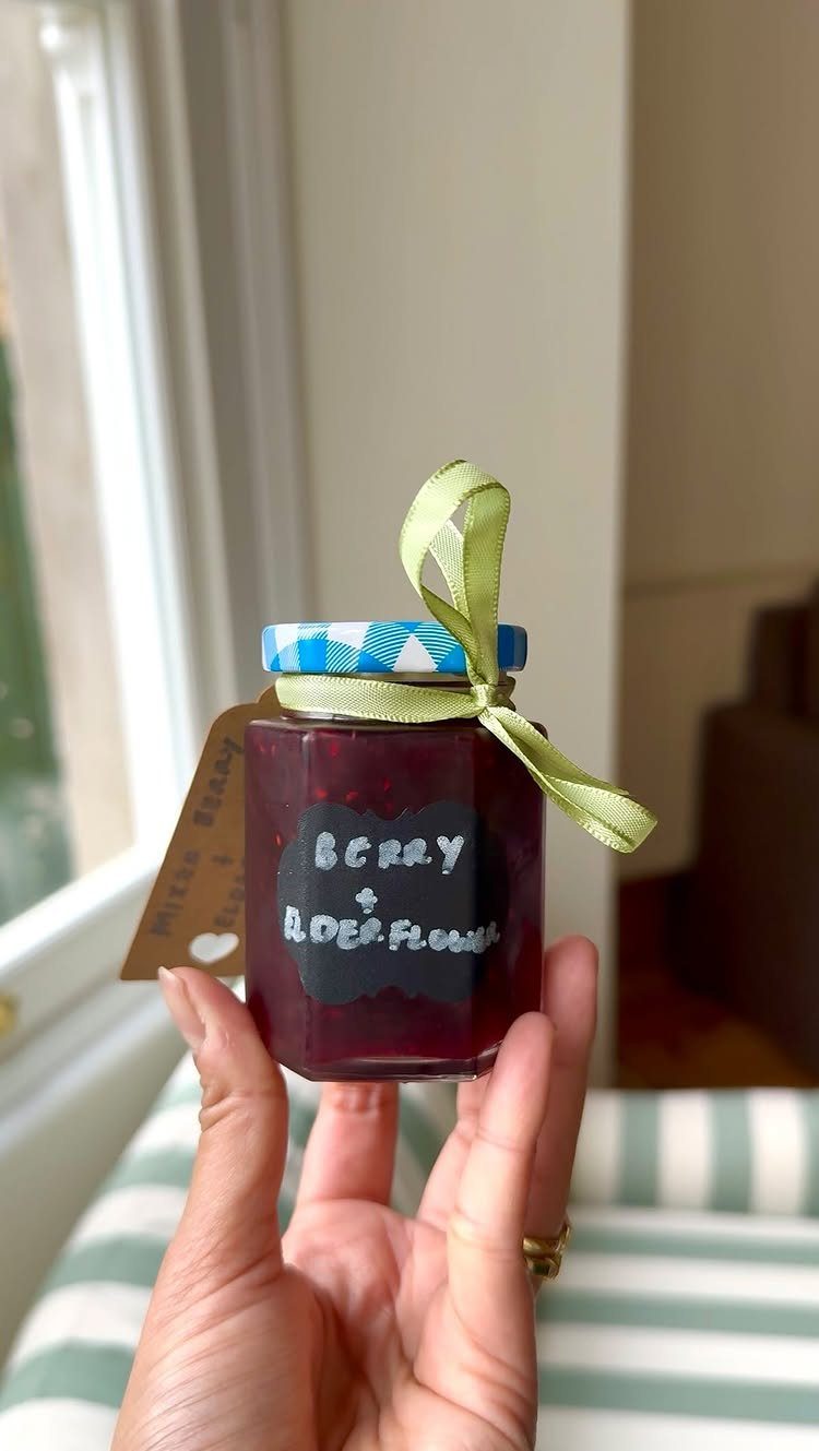 Small hexagonal jar of dark red berry preserve with a green ribbon bow.
