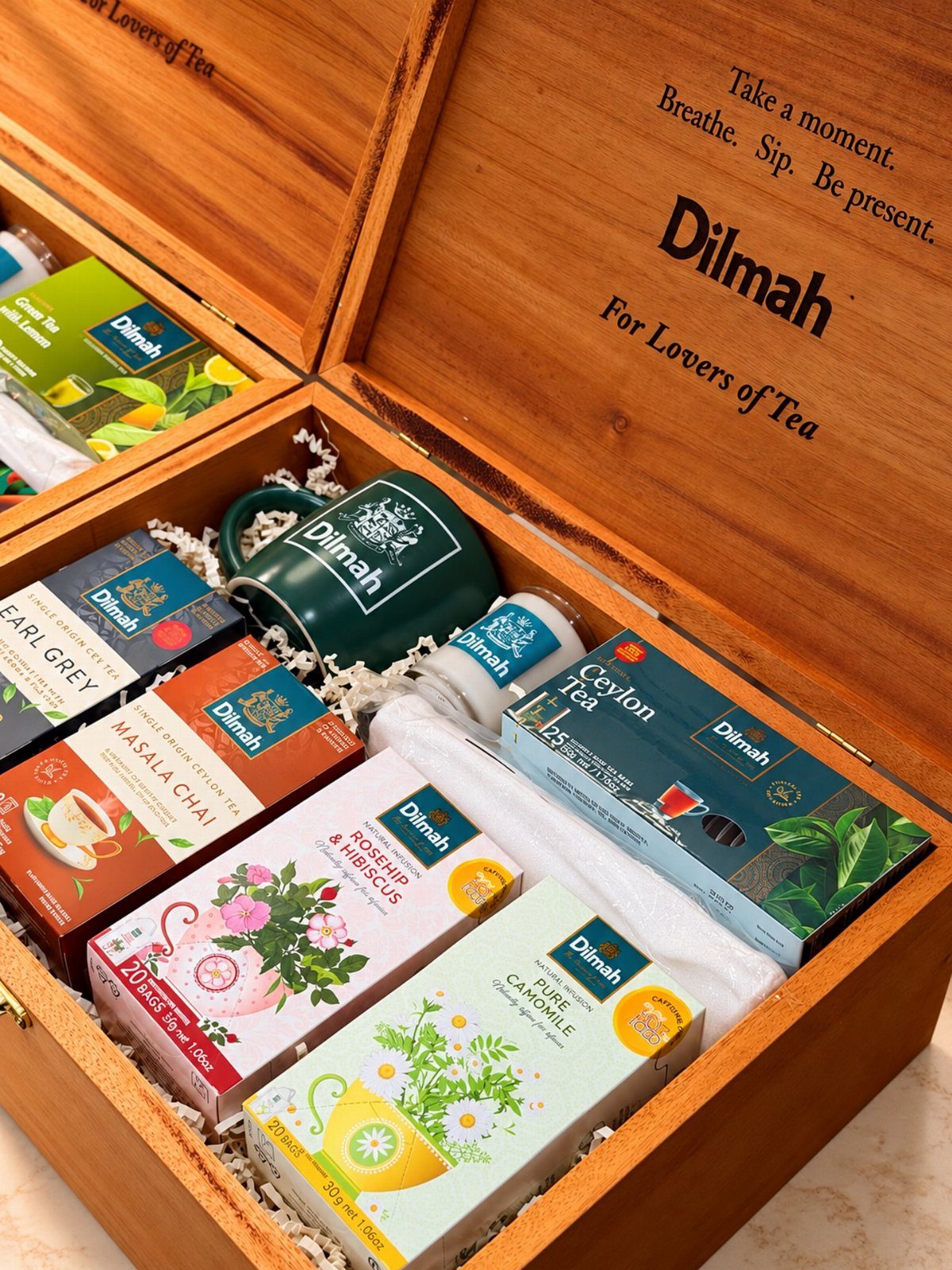 Wooden gift box filled with assorted tea boxes and a green ceramic mug.