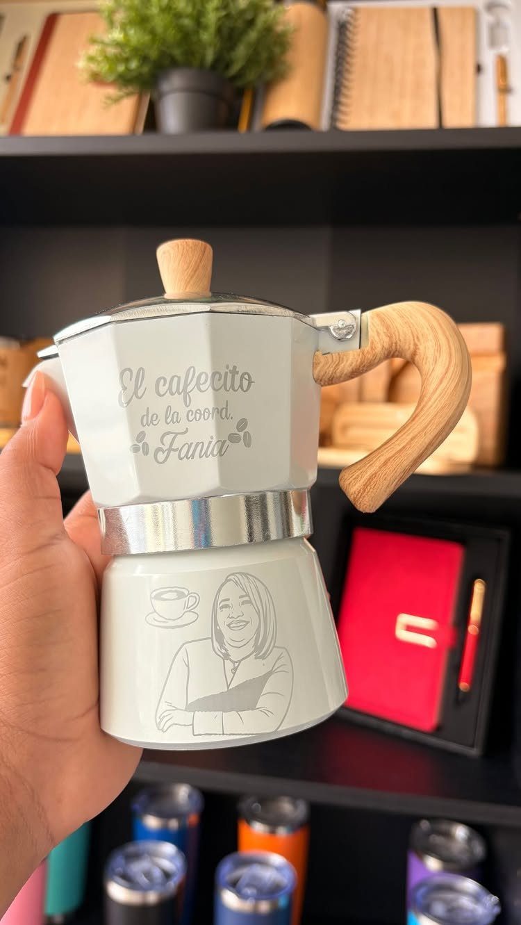 White Moka pot coffee maker with custom illustration and wooden handle held by hand.