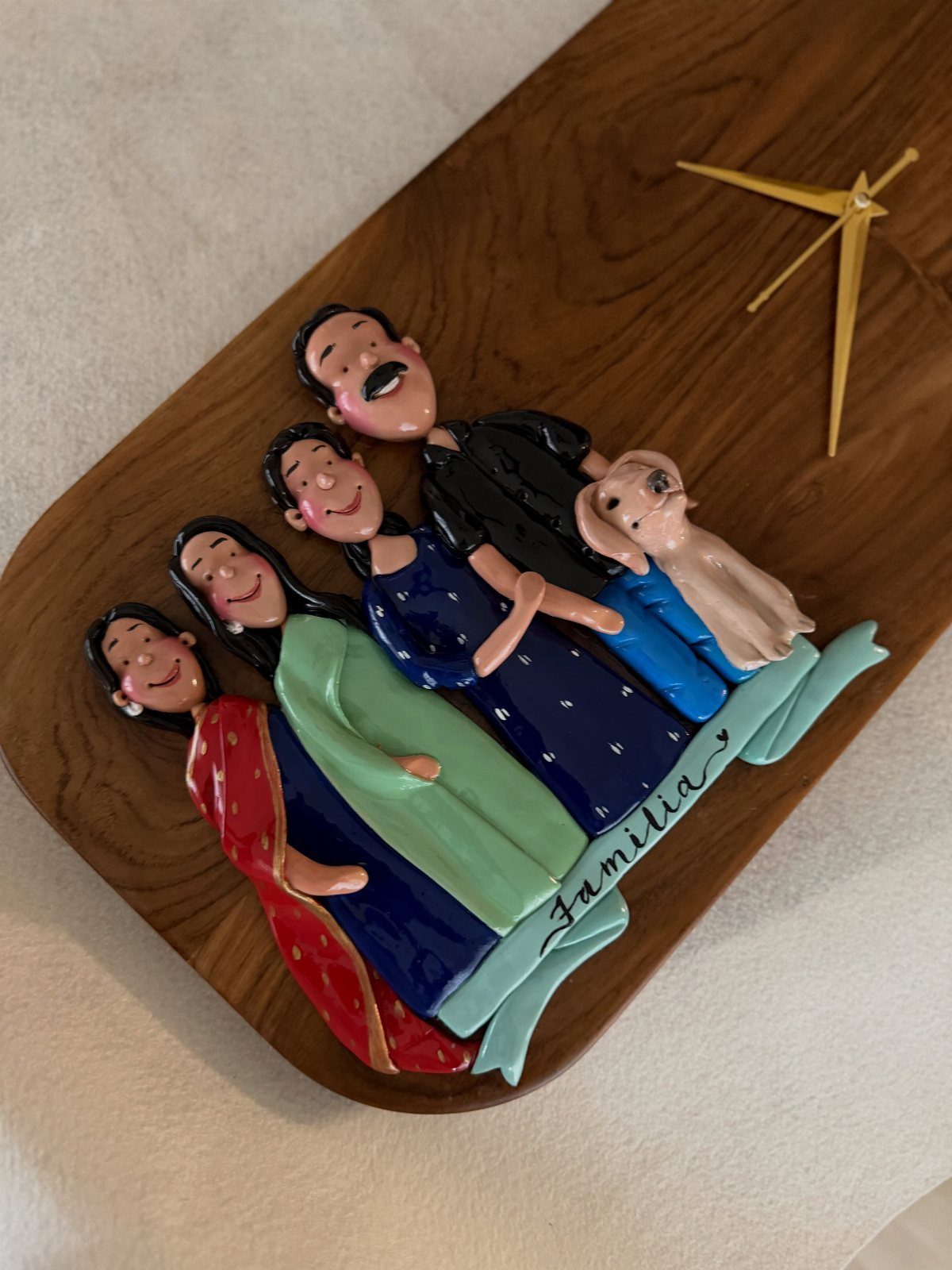 3D clay family sculpture on a wooden base with Familia written on a ribbon