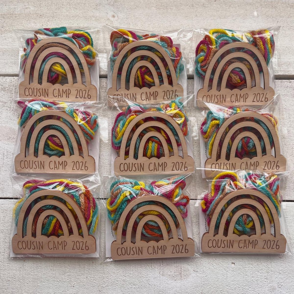 Nine DIY craft kits with colorful yarn and wooden rainbow cutouts for Cousin Camp.