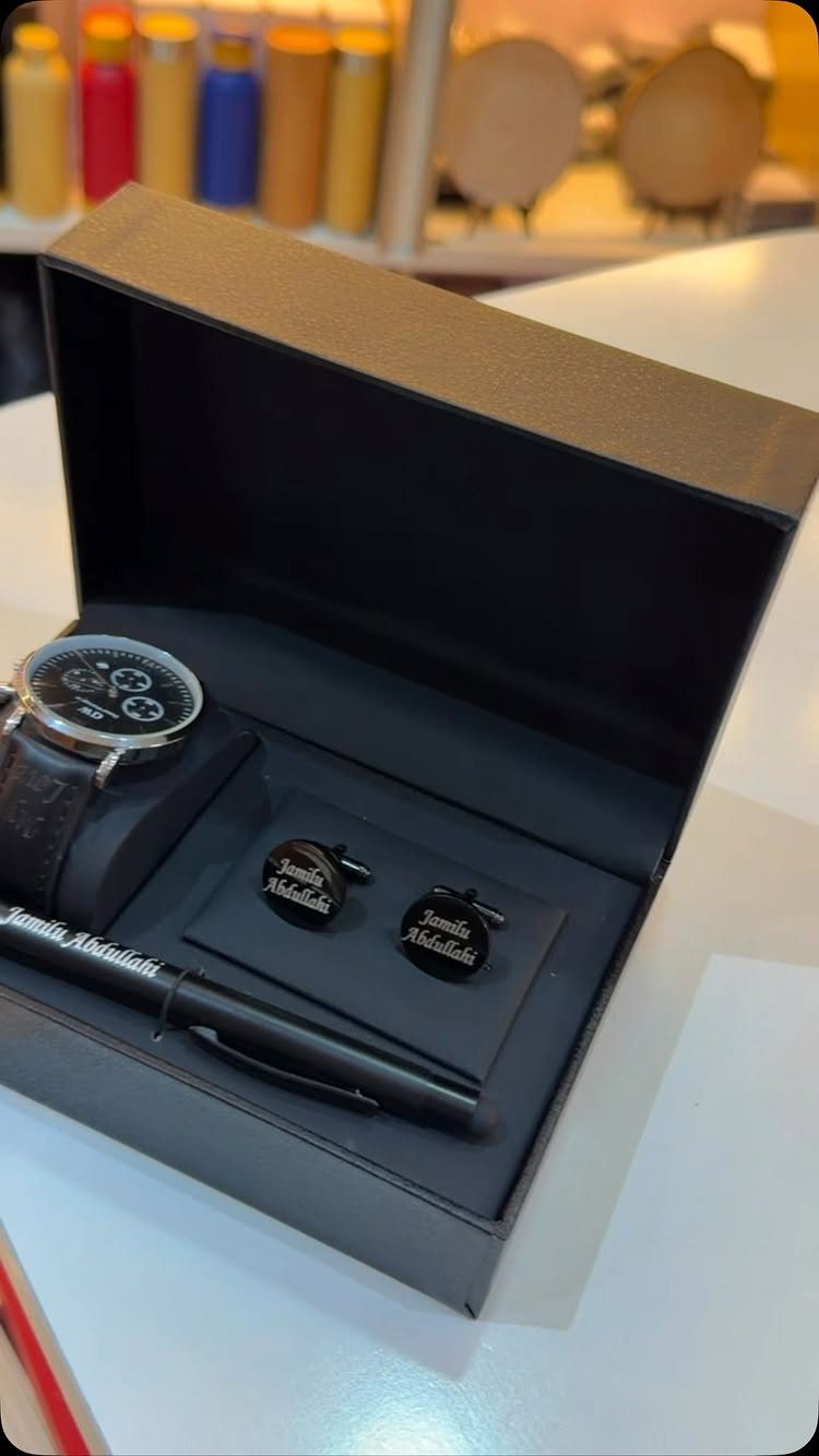 Black gift box with a wristwatch, personalized cufflinks, and a matching black pen.
