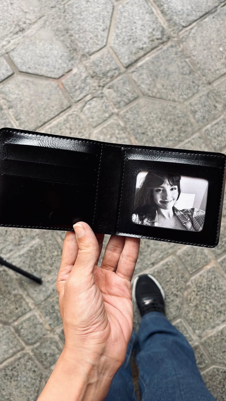 Black leather wallet held open showing a small black and white portrait photo inside.
