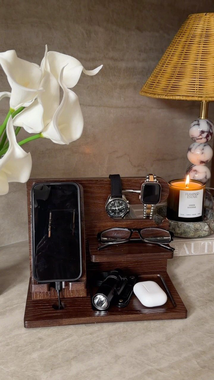 Wooden tech organiser holding a smartphone, watches, glasses, and wireless earbud cases.
