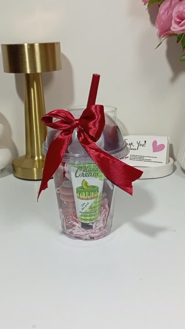 Gift set in a plastic cup with hand cream and a red bow.