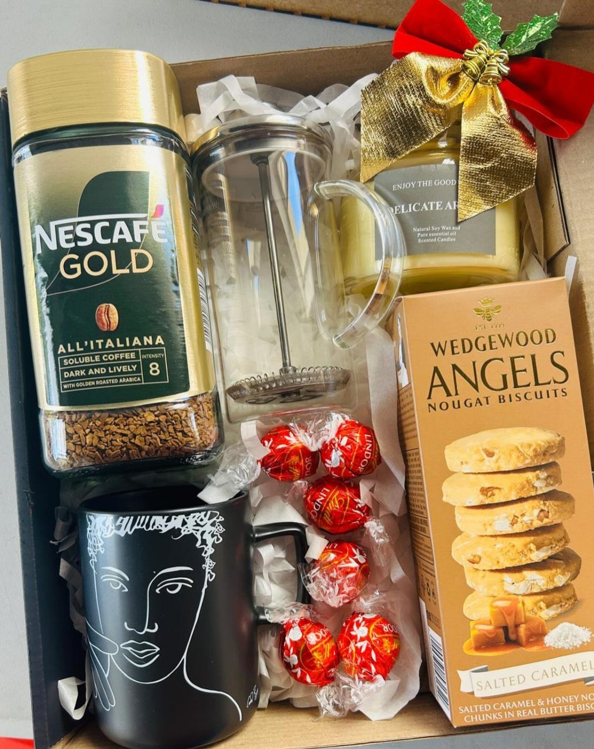 Coffee gift set with Nescafe Gold, French press, black mug, and biscuits in box.