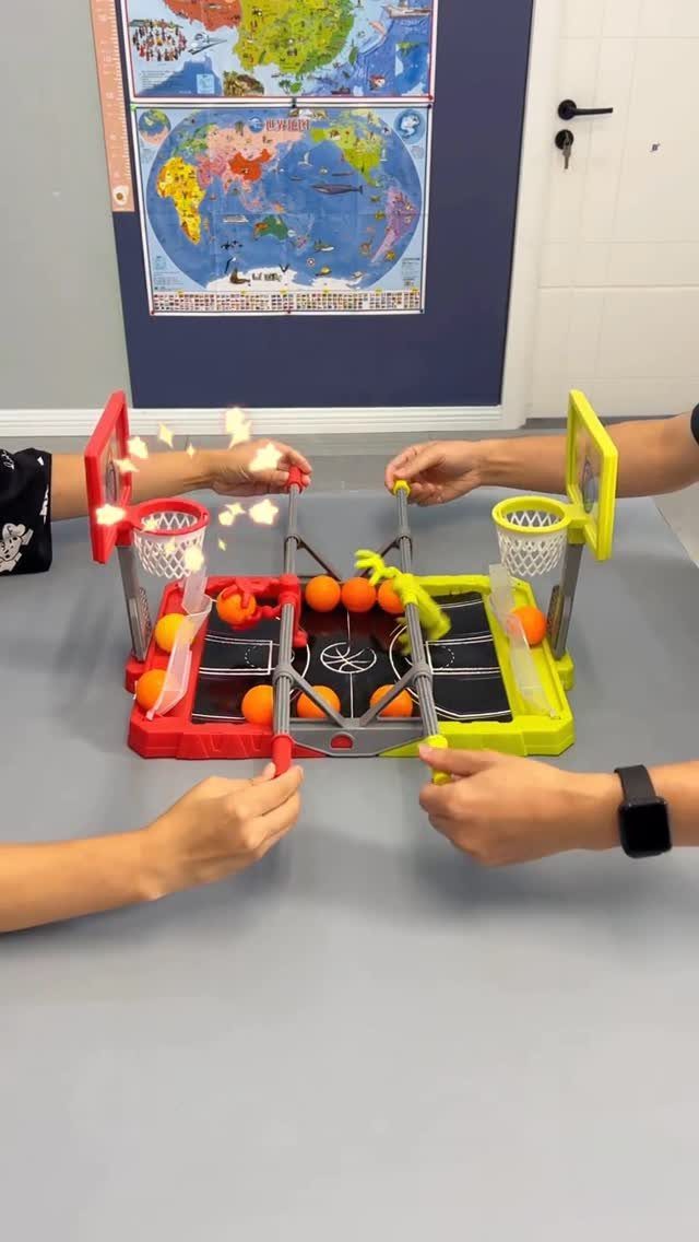 Tabletop basketball game with red and yellow plastic hoops and small orange balls.