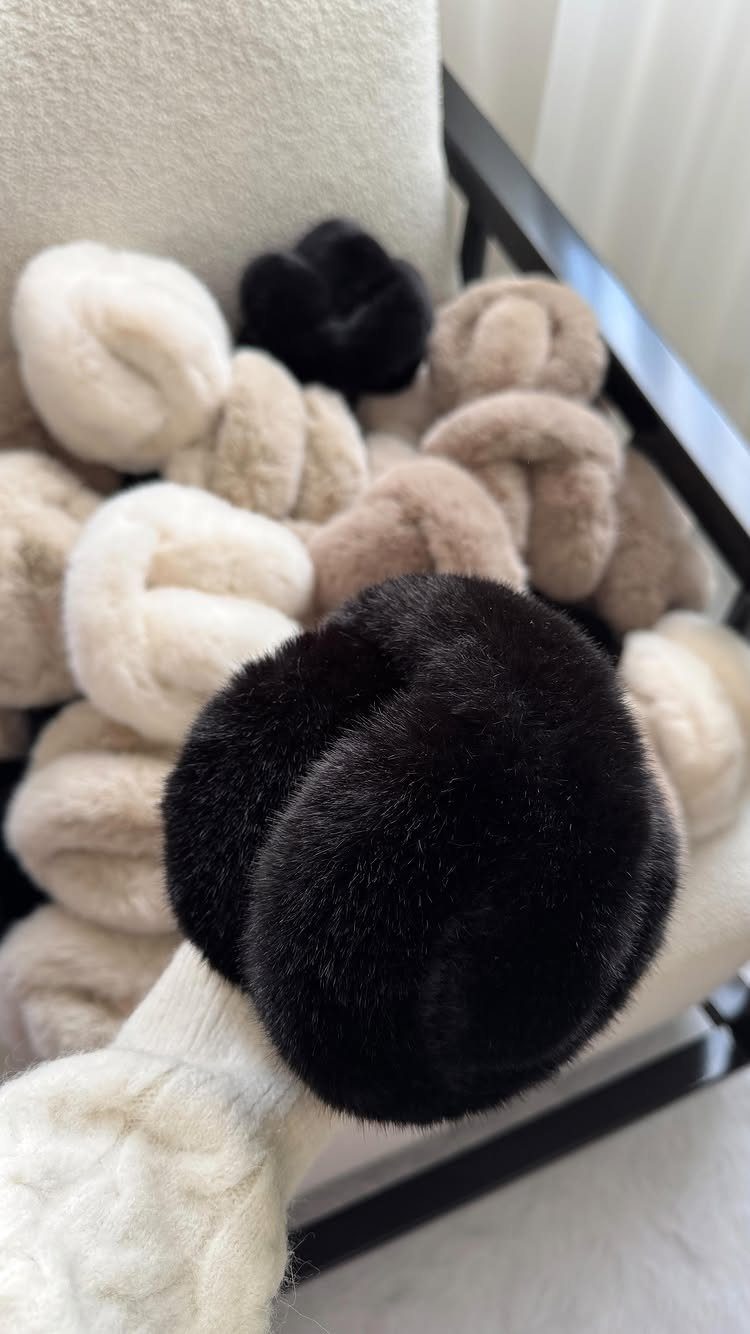 Fluffy faux-fur hair ties in black and cream colors piled on a white chair.