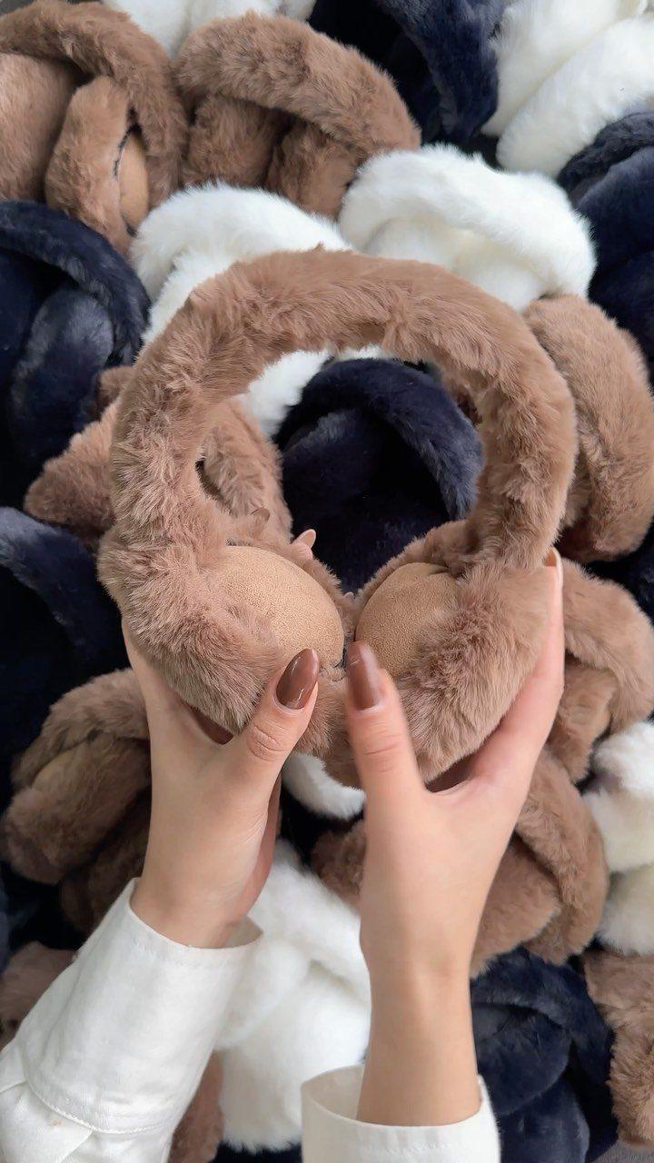 Brown faux-fur headband held over a pile of chunky knit blankets.