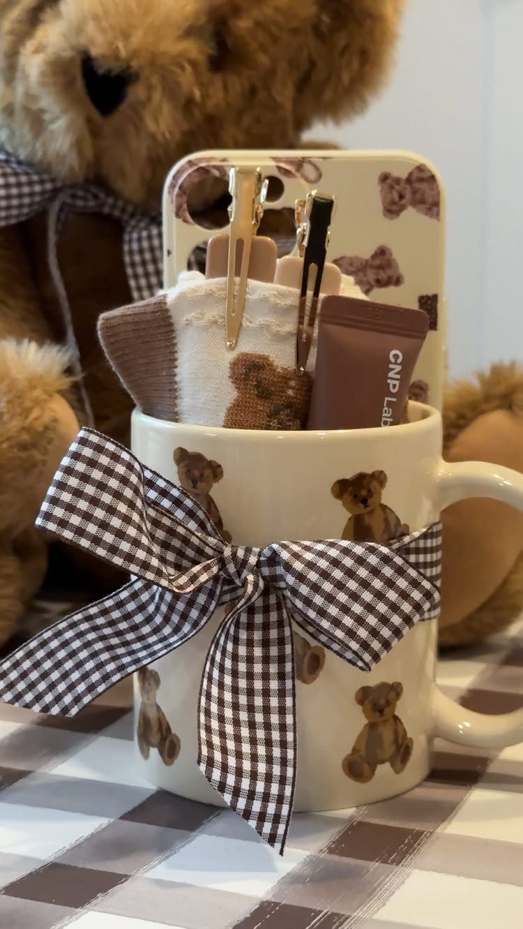 Teddy bear themed ceramic mug filled with small gifts and a gingham bow.