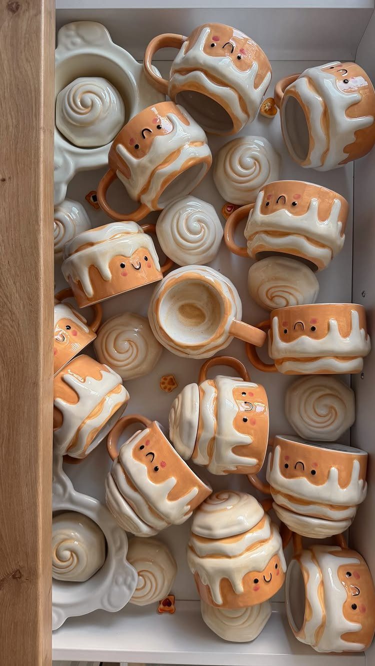 Cute ceramic mugs with smiley faces and cinnamon rolls in a white drawer