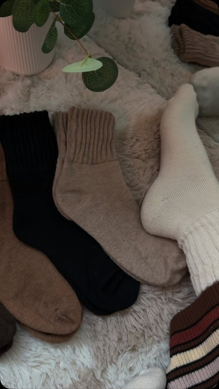 Ribbed knit socks in neutral colors resting on a white fluffy faux-fur rug.