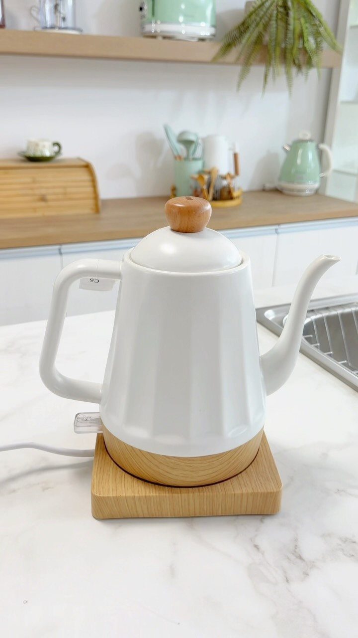 White electric kettle with wooden base on a white marble kitchen countertop