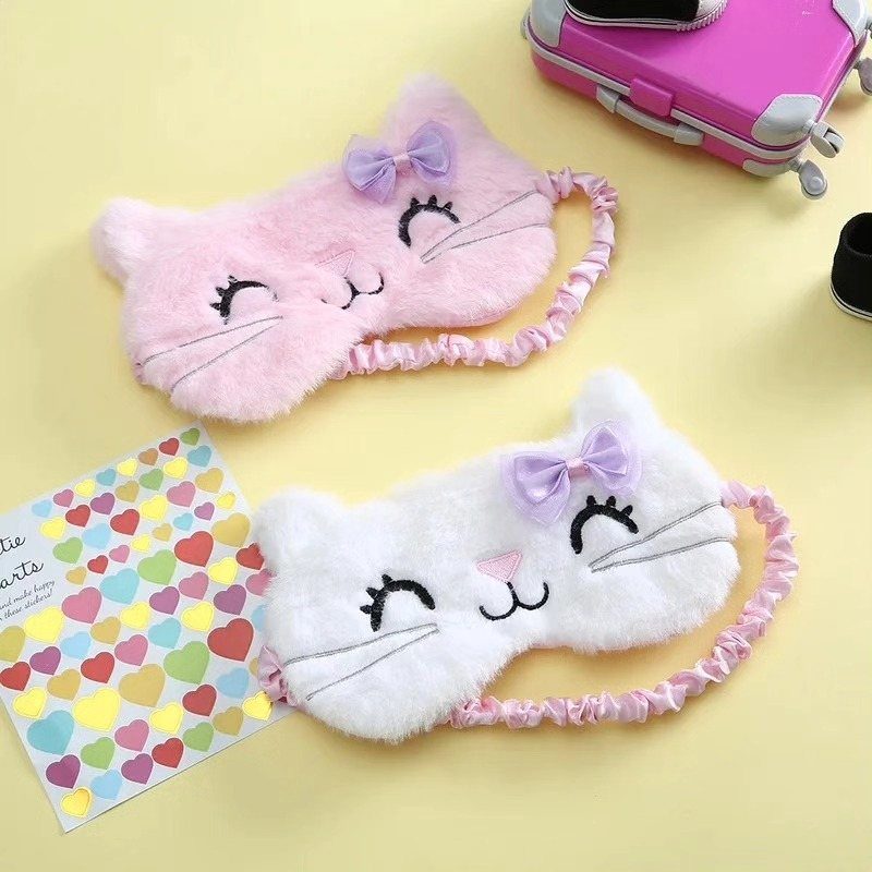 Two fluffy cat sleep masks in pink and white on a yellow background.