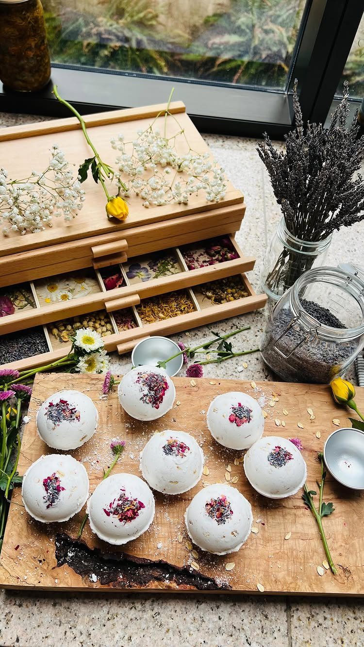 White bath bombs with dried purple petals on a wooden board with lavender.